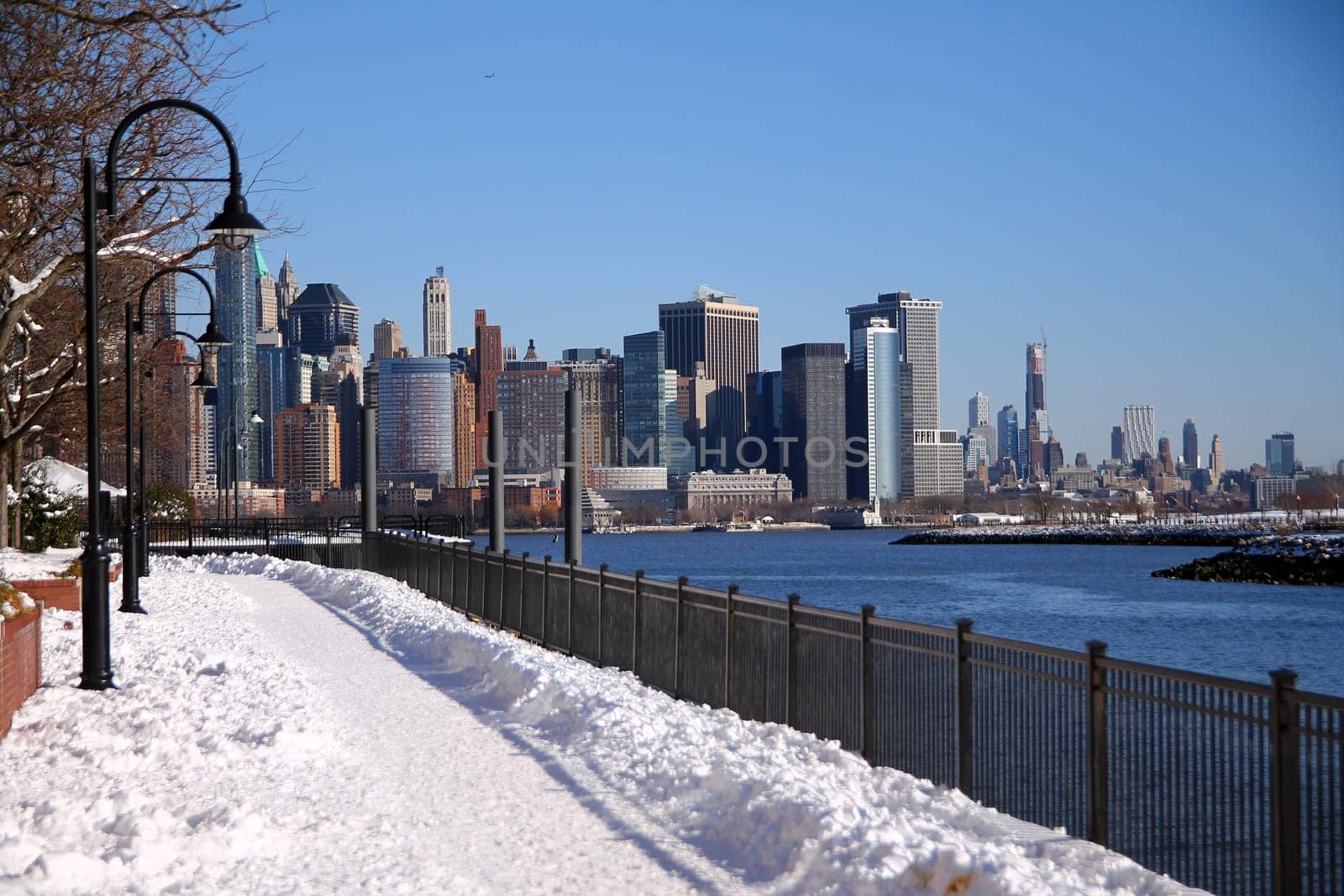 The snow path of the Hudson river walkaway with downtown Manhattan on the back from Paulus Hook in Jersey City