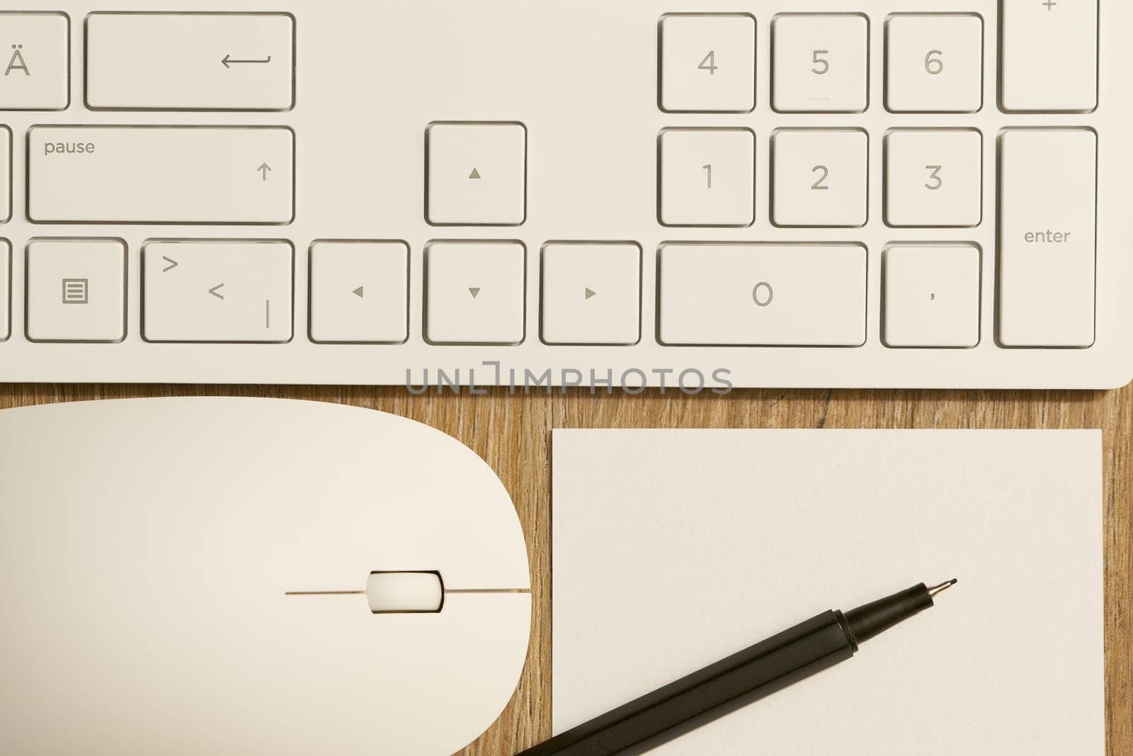 Keyboard from a computer and a computer mouse and pen and paper on a desk in the office