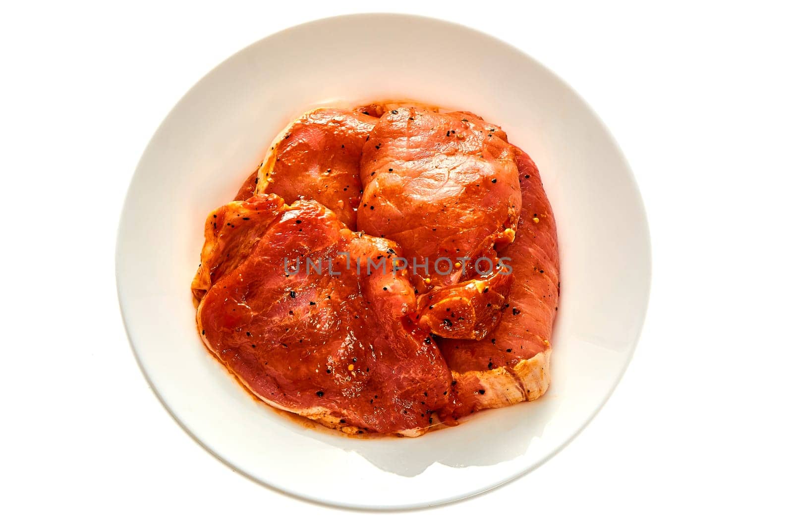 Pork in marinade lies on a white plate on a white isolated background. High quality photo