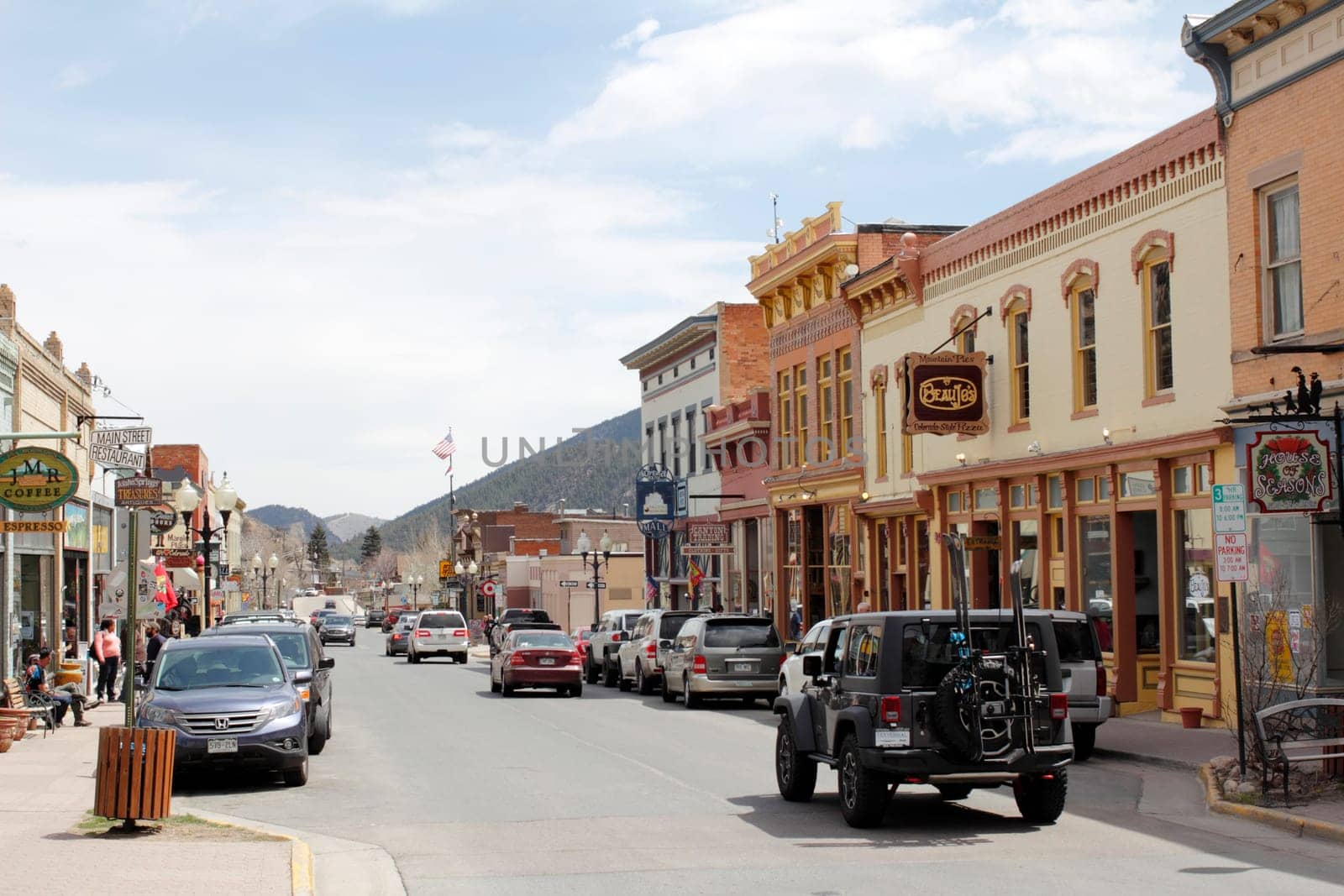 Idaho Springs, CO, USA - April 19, 2014: A sunny, commercial area of Miner Street where a lot of stores and shopping happens. Many people, merchants and vehicles line the downtown shopping area sunny street on a day in spring.