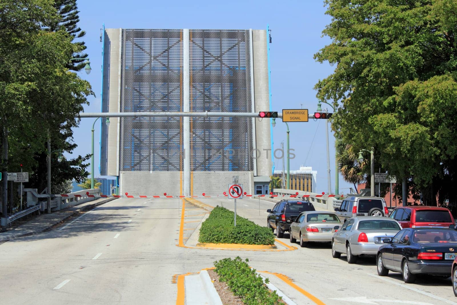 LAUDERDALE-BY-THE-SEA, FL, USA - APRIL 7, 2014: A drawbridge is raised straight up and cars wait patiently on the east side of the Intracoastal Waterway on Commercial Boulevard on a sunny day. Vehicles wait for the raised drawbridge to lower so they can pass over the Intracoastal waterway.