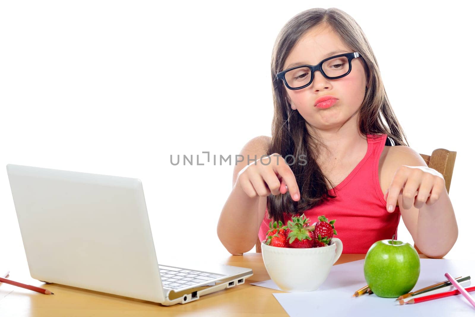 a little girl at her desk looking at his snack on white