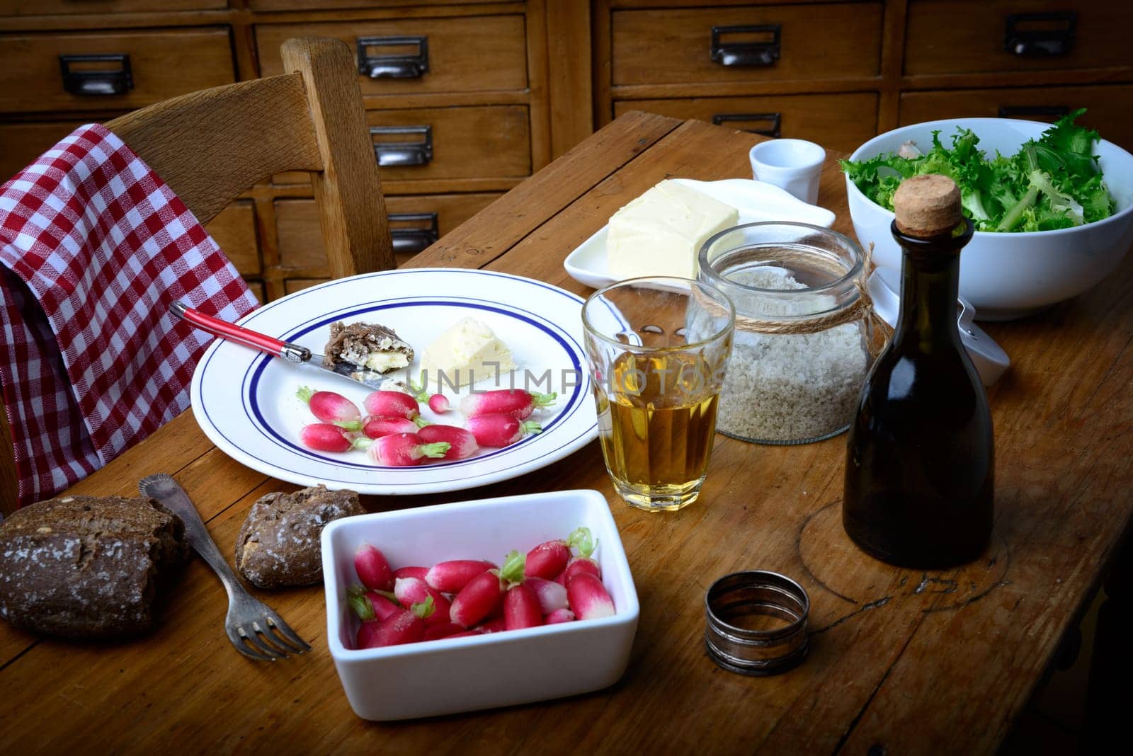plate with radish, butter and salad on old table