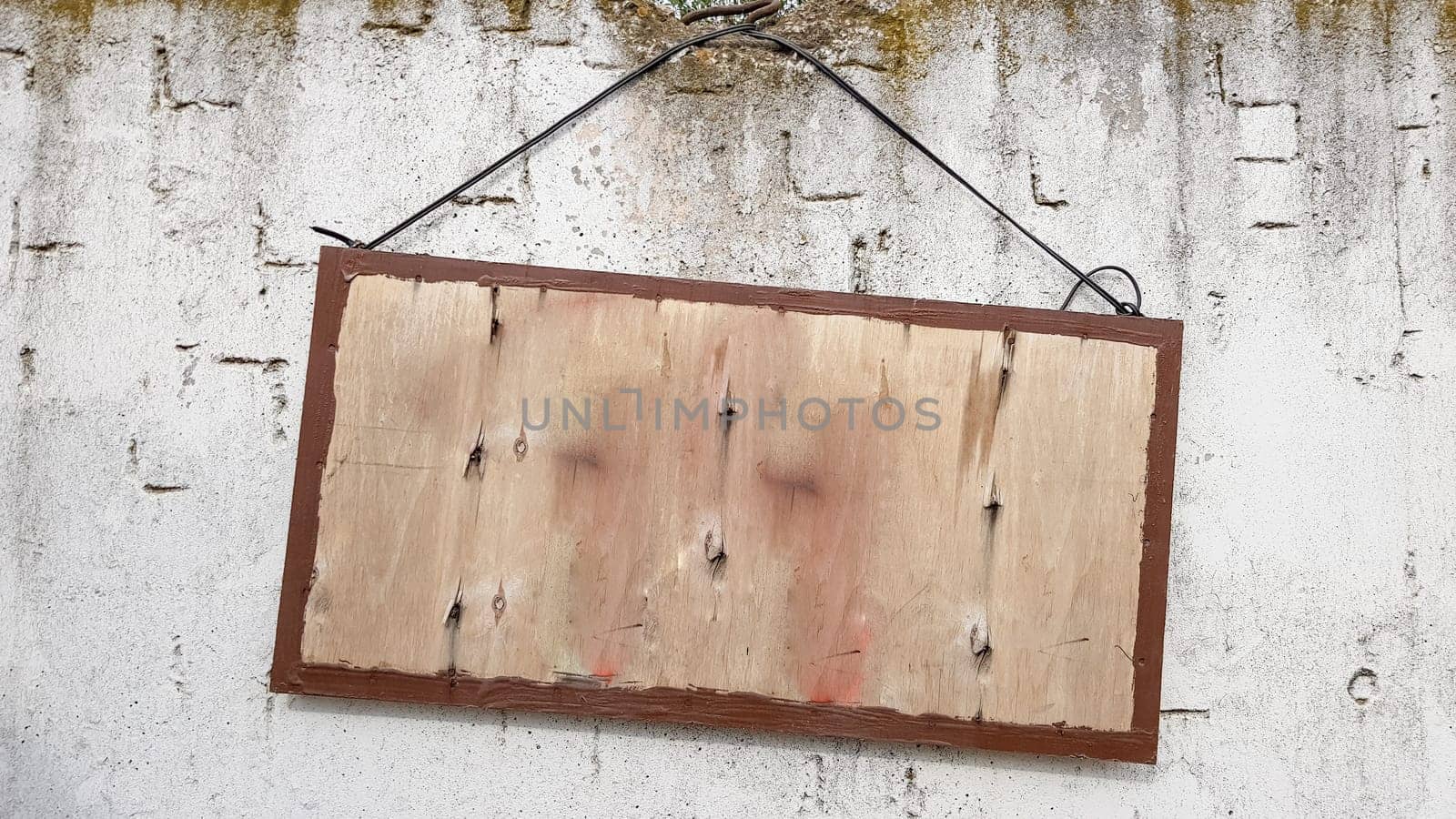 hanging wooden sign on a gray concrete wall. frame on a cement wall. A large wooden sign hanging on a rope with a concrete wall. Copy space
