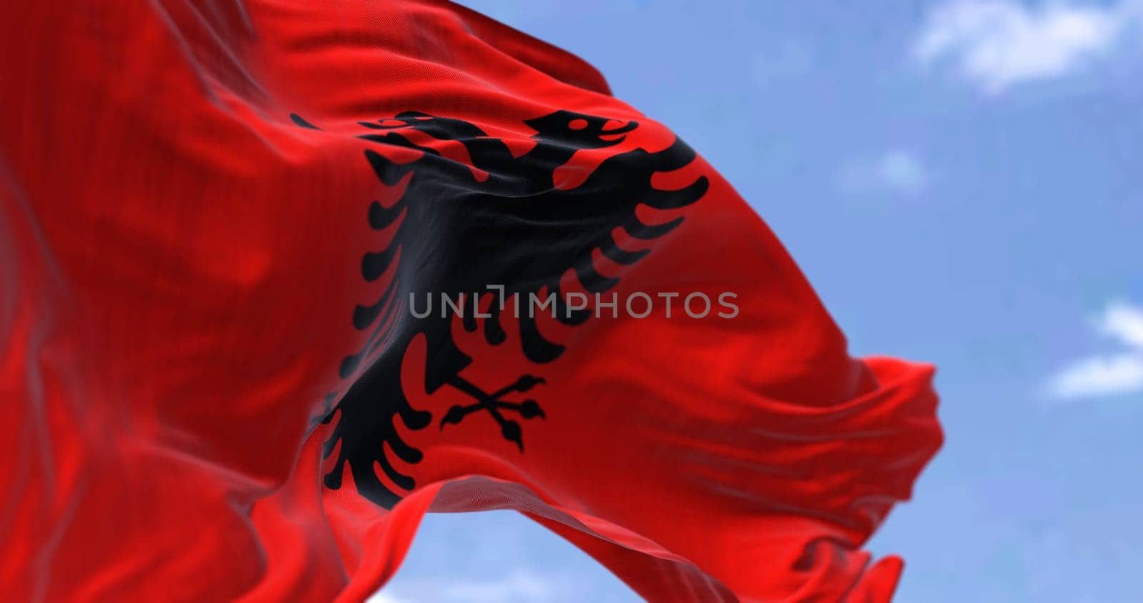 Detail of the national flag of Albania waving in the wind on a clear day. Democracy and politics. Patriotism. European country. Selective focus. Southeastern European country