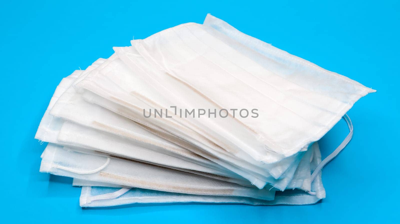 Coronavirus protection. Antiviral protective medical face masks with ear loops. Surgical mask background. Respiratory syndrome, coronavirus disease COVID-19. Many folded medical masks