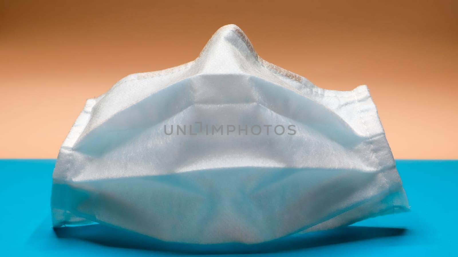One 3-layer disposable surgical face mask with rubber pads to cover the mouth and nose. The concept of protection from bacteria, healthcare and medicine. COVID-19. Dangerous virus.