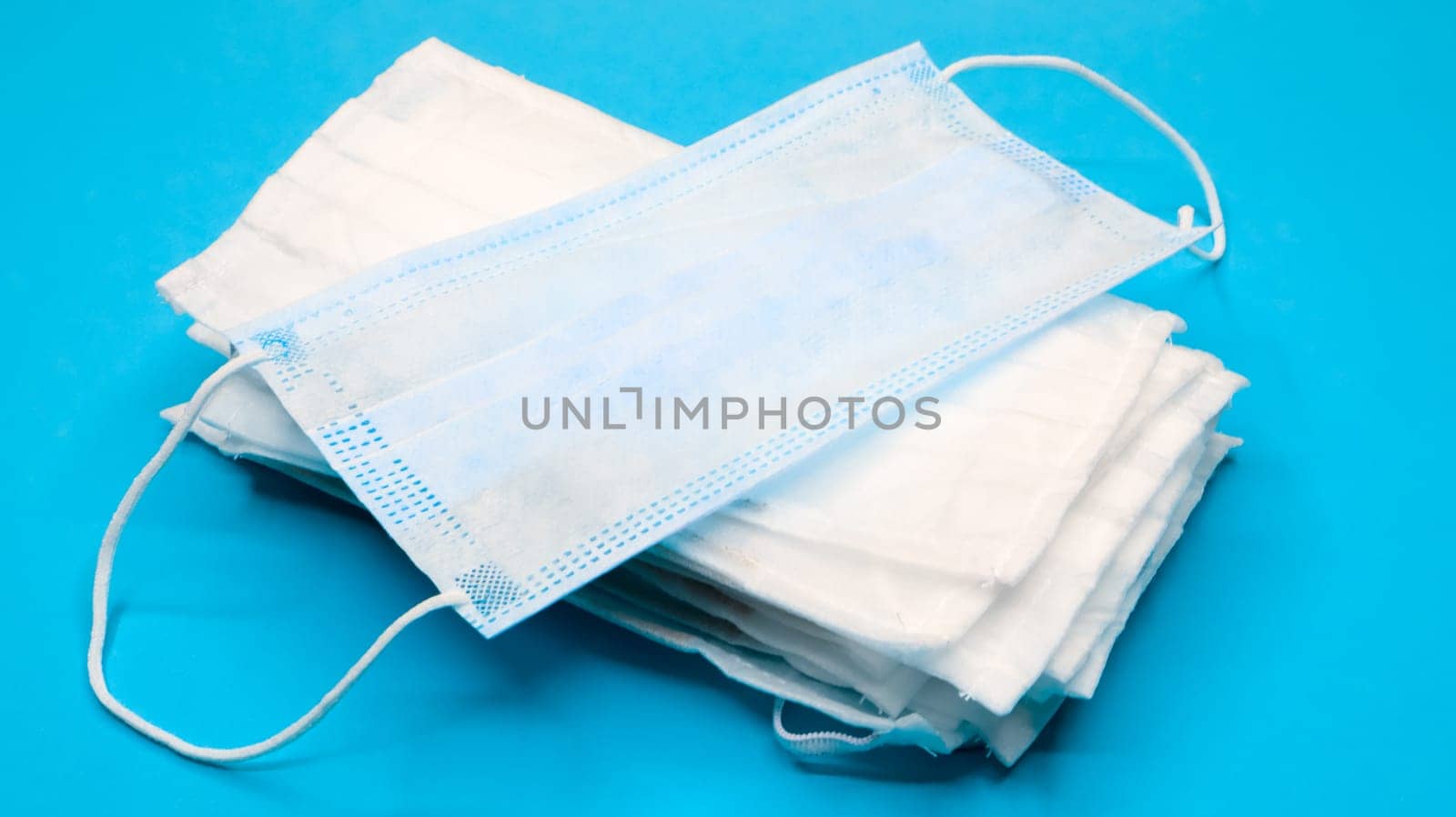 Coronavirus protection. Antiviral protective medical face masks with ear loops. Surgical mask background. Respiratory syndrome, coronavirus disease COVID-19. Many folded medical masks