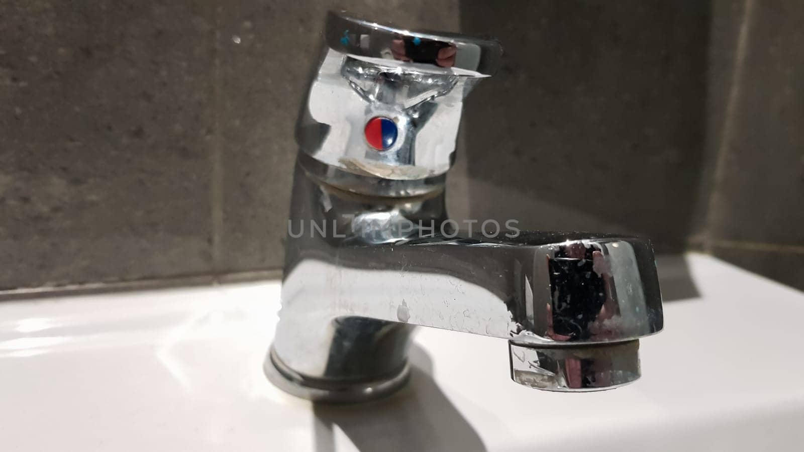 white ceramic washbasin with chrome faucet in the toilet with gray tile.