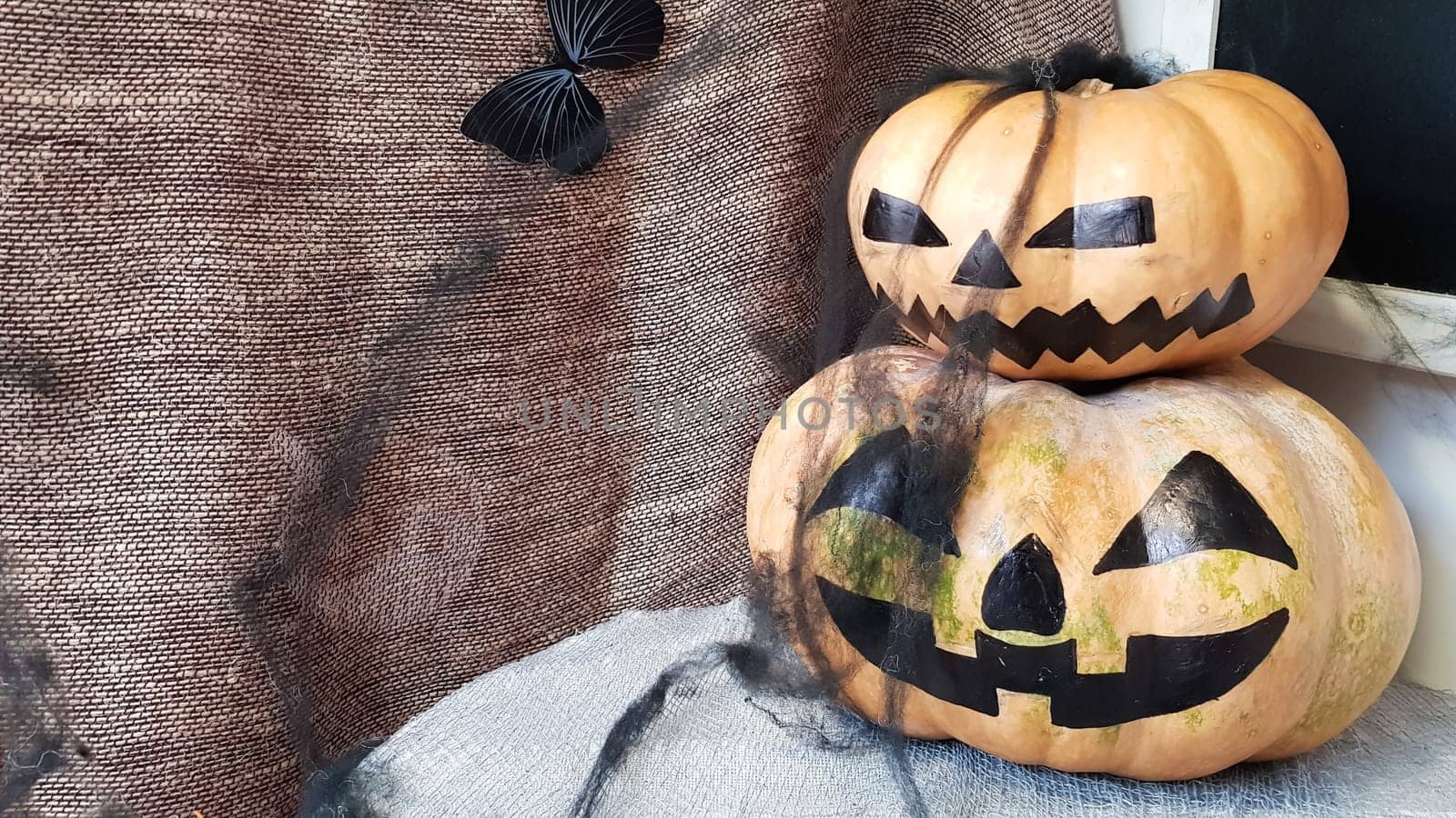 Pumpkin with a scary face on a wooden table. The interior of the house is decorated with pumpkins and spider webs for the holiday of Halloween