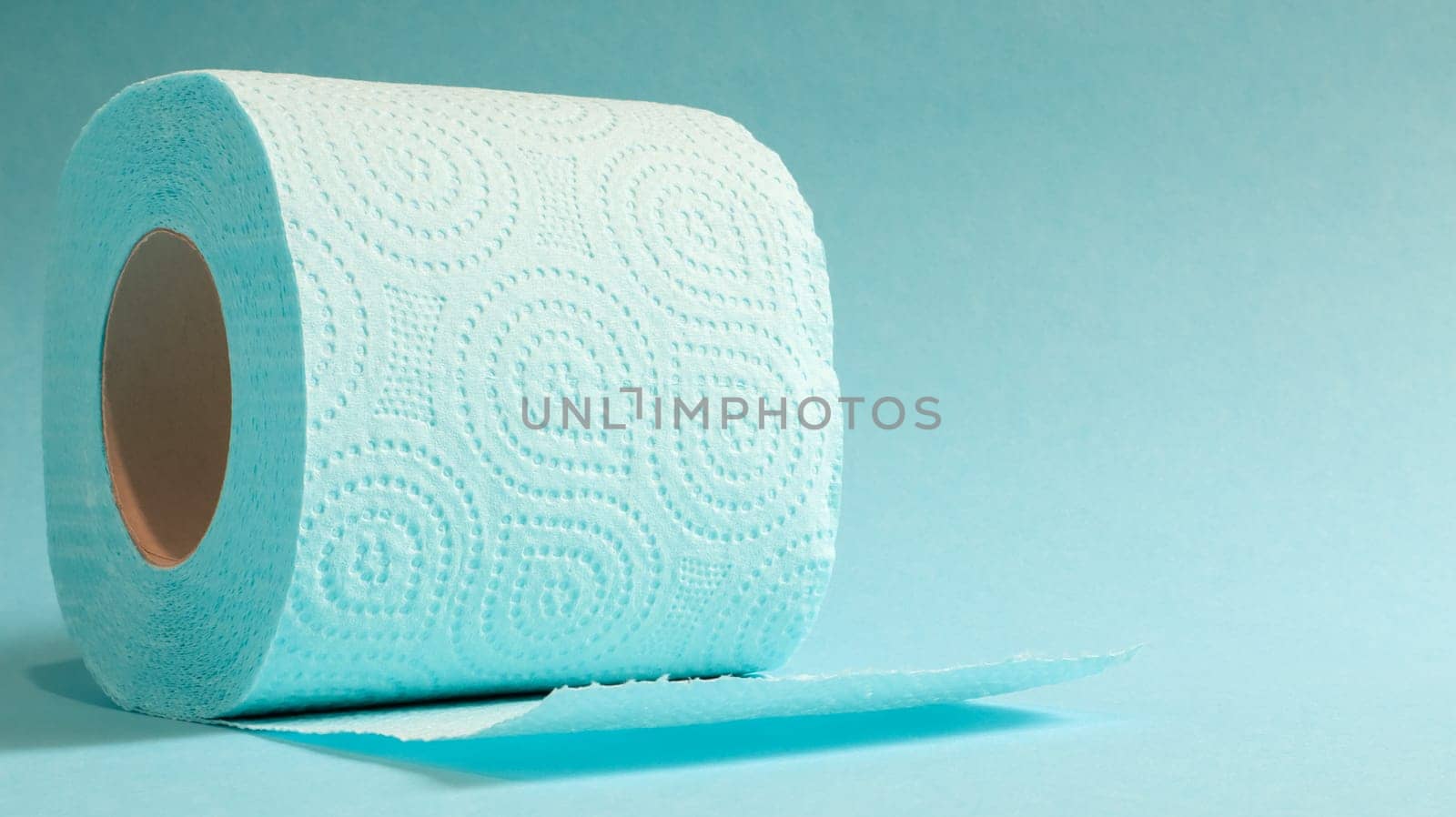 Blue roll of modern toilet paper on a blue background. A paper product on a cardboard sleeve, used for sanitary purposes from cellulose with cutouts for easy tearing. Embossed drawing. copy space
