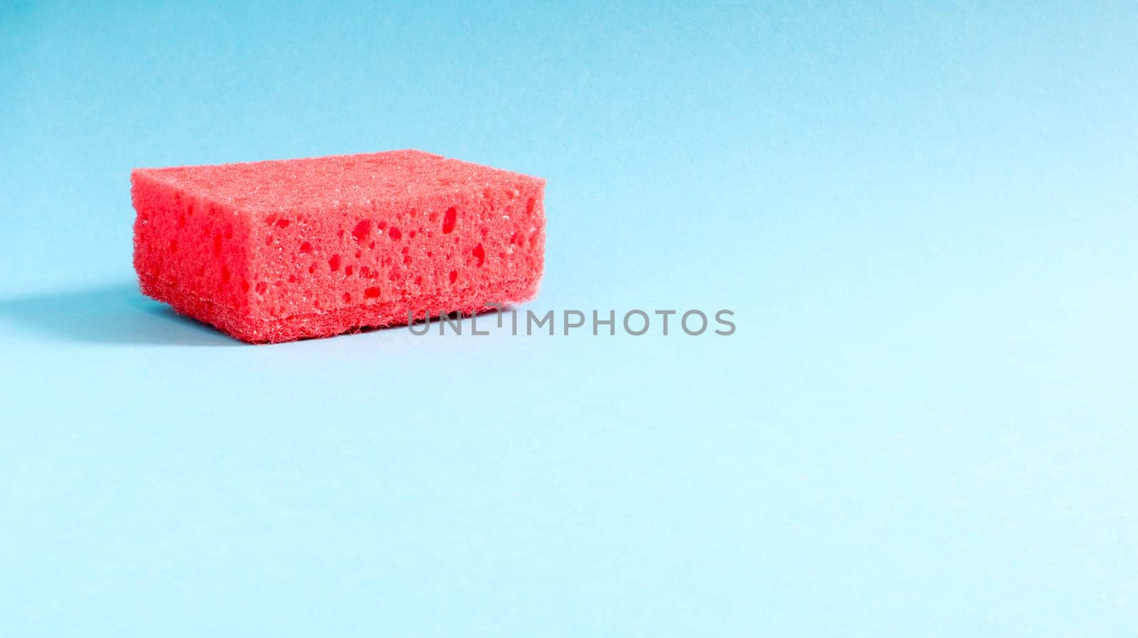 One red sponge on a blue background is used to wash and erase the dirt used by housewives in everyday life. They are made of porous material. Saving detergent, which allows you to use it sparingly.