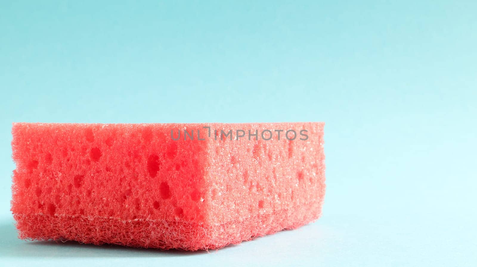 One red sponge on a blue background is used to wash and erase the dirt used by housewives in everyday life. They are made of porous material. Saving detergent, which allows you to use it sparingly.