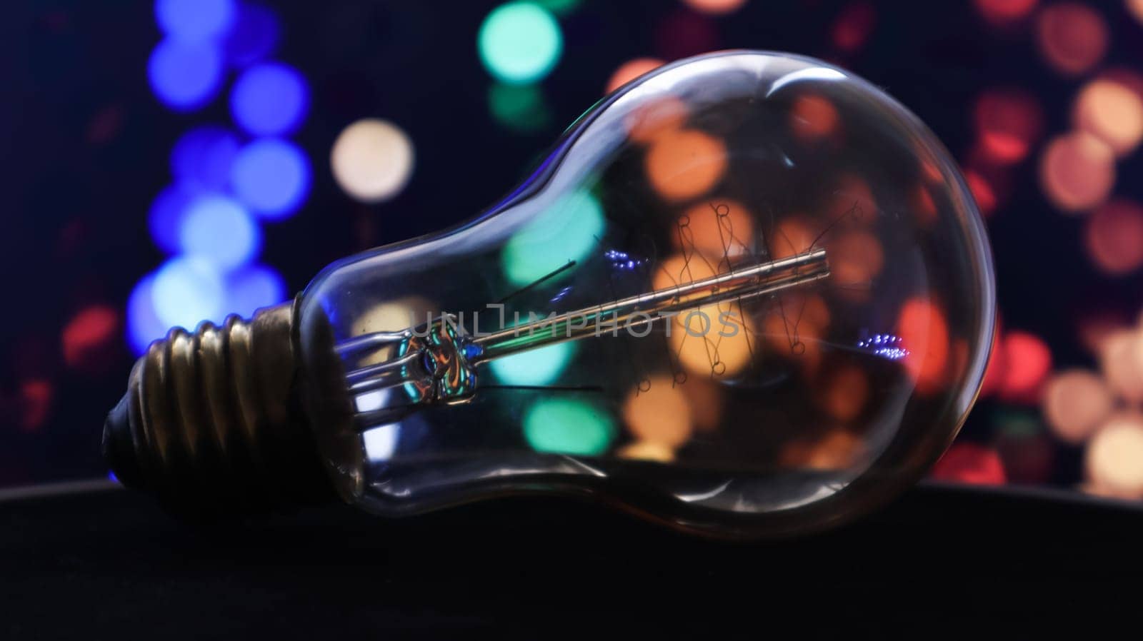 One light bulb lies on a black background with lights in the background. Creative ideas concept. Colorful background with flickering light bulbs. Holiday concept. New Year's and Christmas.