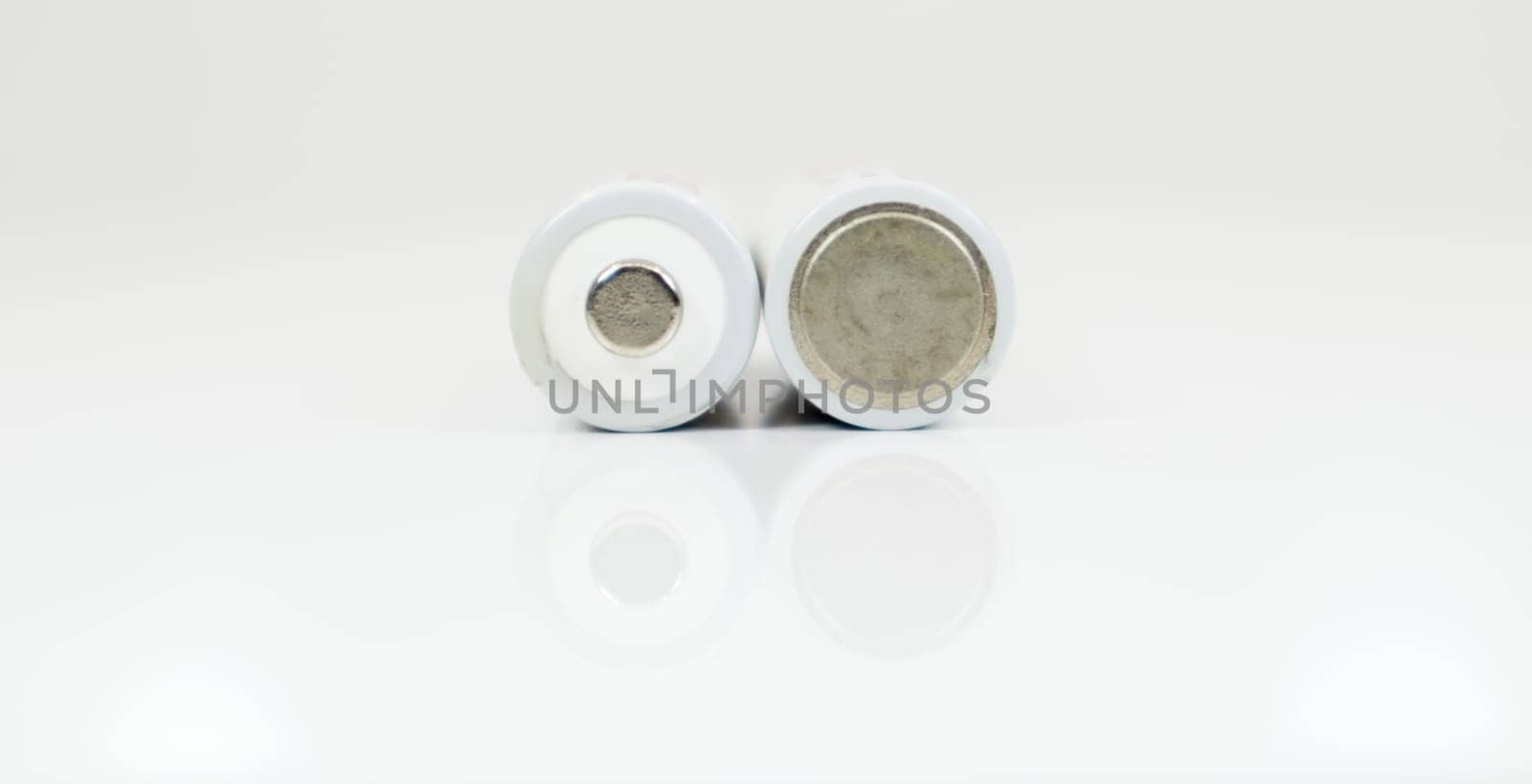 Two alkaline batteries on a white background with reflection. Energy supply and recycling concept. Copy space. Minimalism. Eliment AA is the most common type of galvanic batteries and accumulators