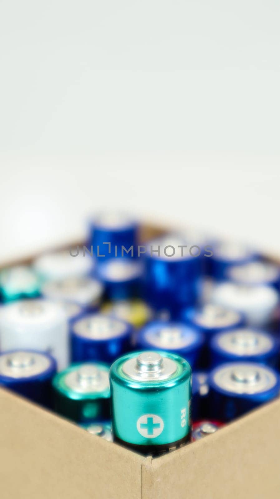 A cardboard box on a white background full of used household AA, AAA alkaline batteries collected for recycling. Recycling and ecology problems