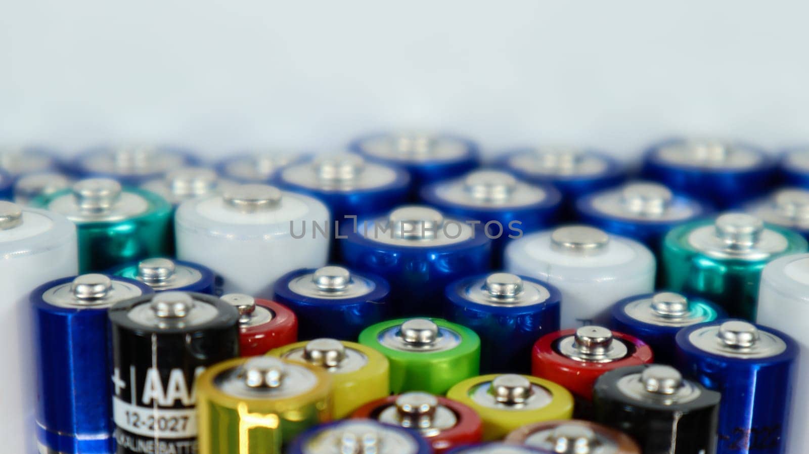 Lots of AA and AAA alkaline batteries on a white background. Ecological recycling concept. The terminals of the disposable batteries are close together and form a beautiful backdrop. Energy source