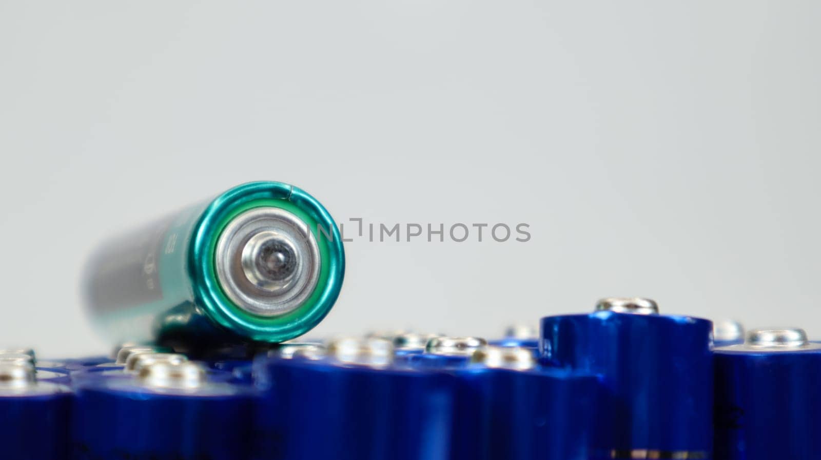 Lots of AA and AAA alkaline batteries on a white background. Ecological recycling concept. The terminals of the disposable batteries are close together and form a beautiful backdrop. Energy source