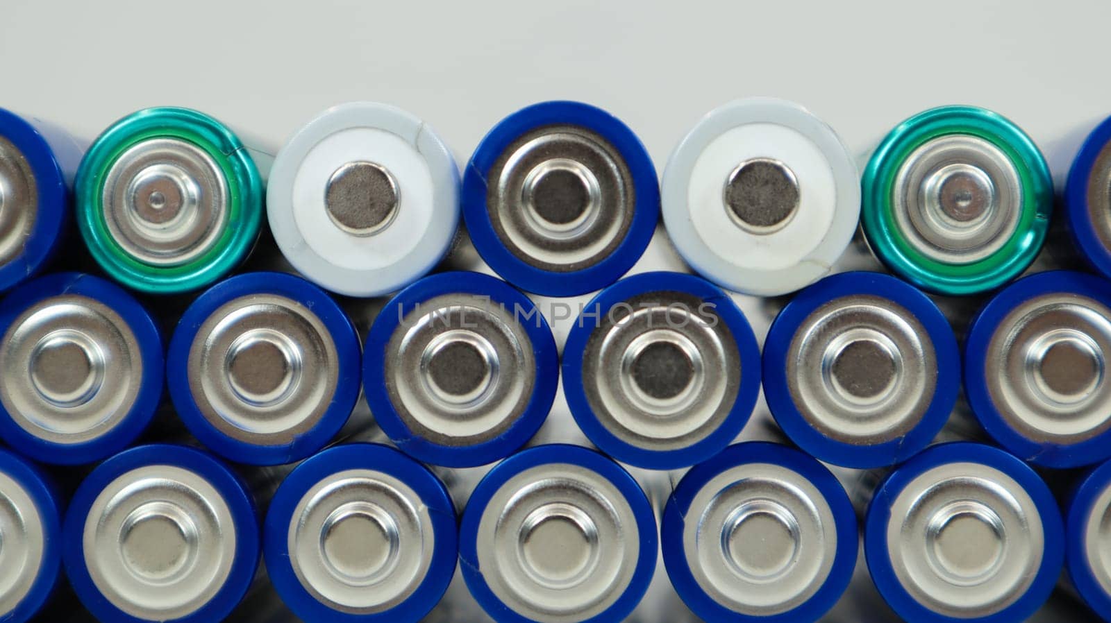 Lots of AA and AAA alkaline batteries on a white background. Ecological recycling concept. The terminals of the disposable batteries are close together and form a beautiful backdrop. Energy source