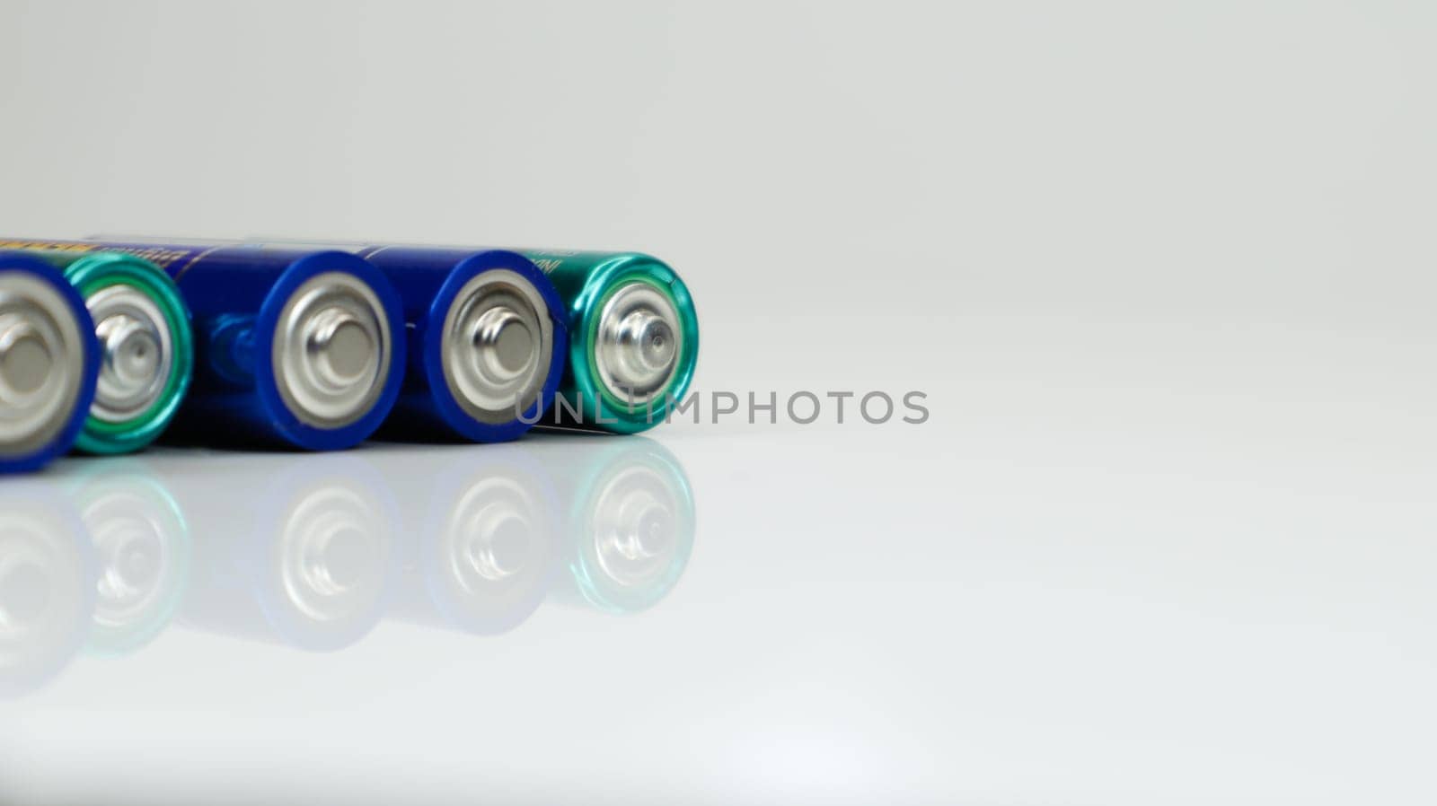 AA alkaline rechargeable batteries on white glossy background with reflection with copy space