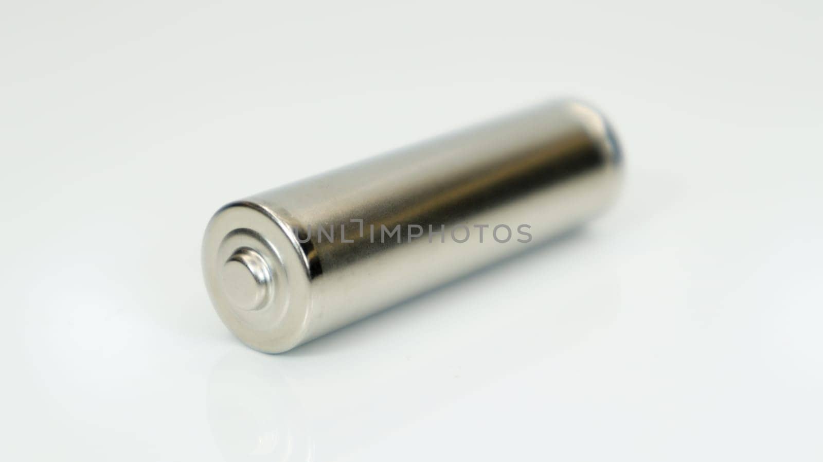 AA alkaline rechargeable battery on white glossy background with reflection. Close one empty battery with copy space