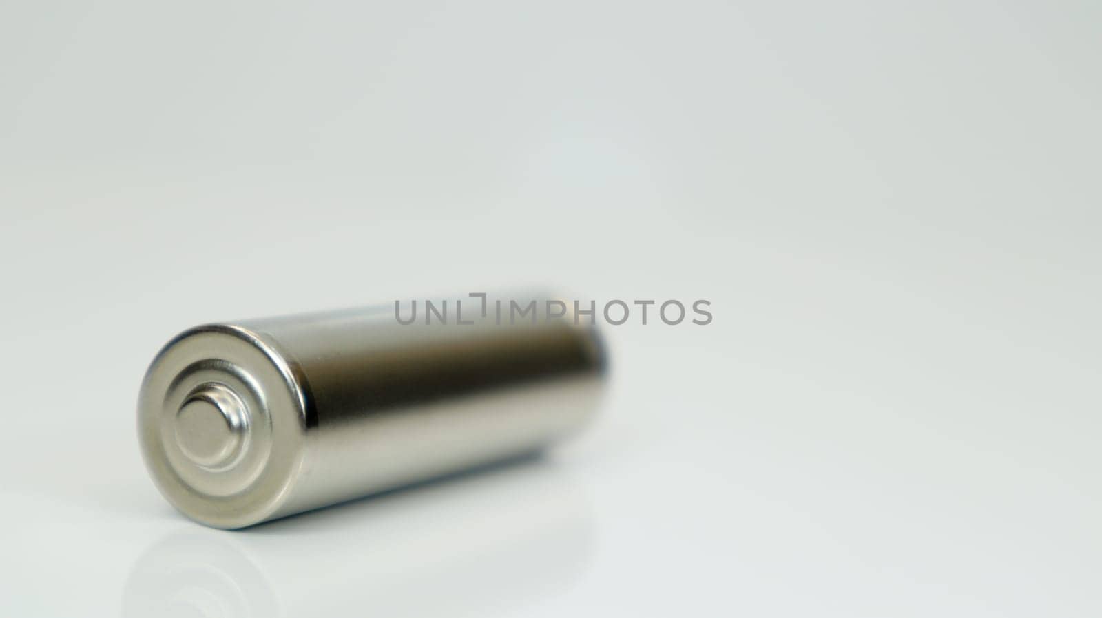 AA alkaline rechargeable battery on white glossy background with reflection. Close one empty battery with copy space