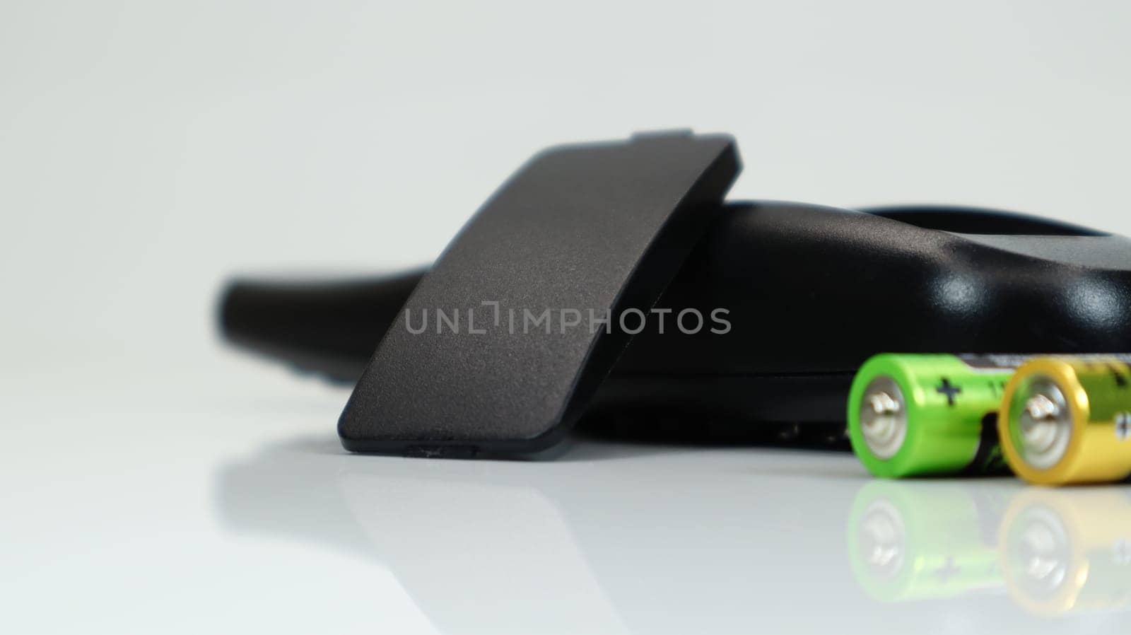 Black TV remote control with AAA alkaline batteries on a white background. Battery replacement, spare parts. Close up of the battery compartment of the remote control