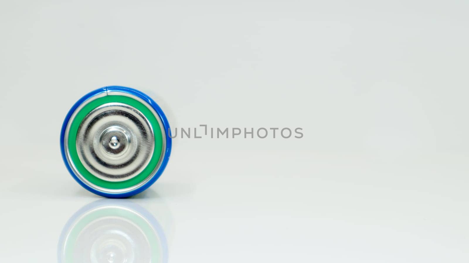 Large battery type D or C cell on white background with reflection. View of a metallic alkaline battery with copy space. Mandatory processing