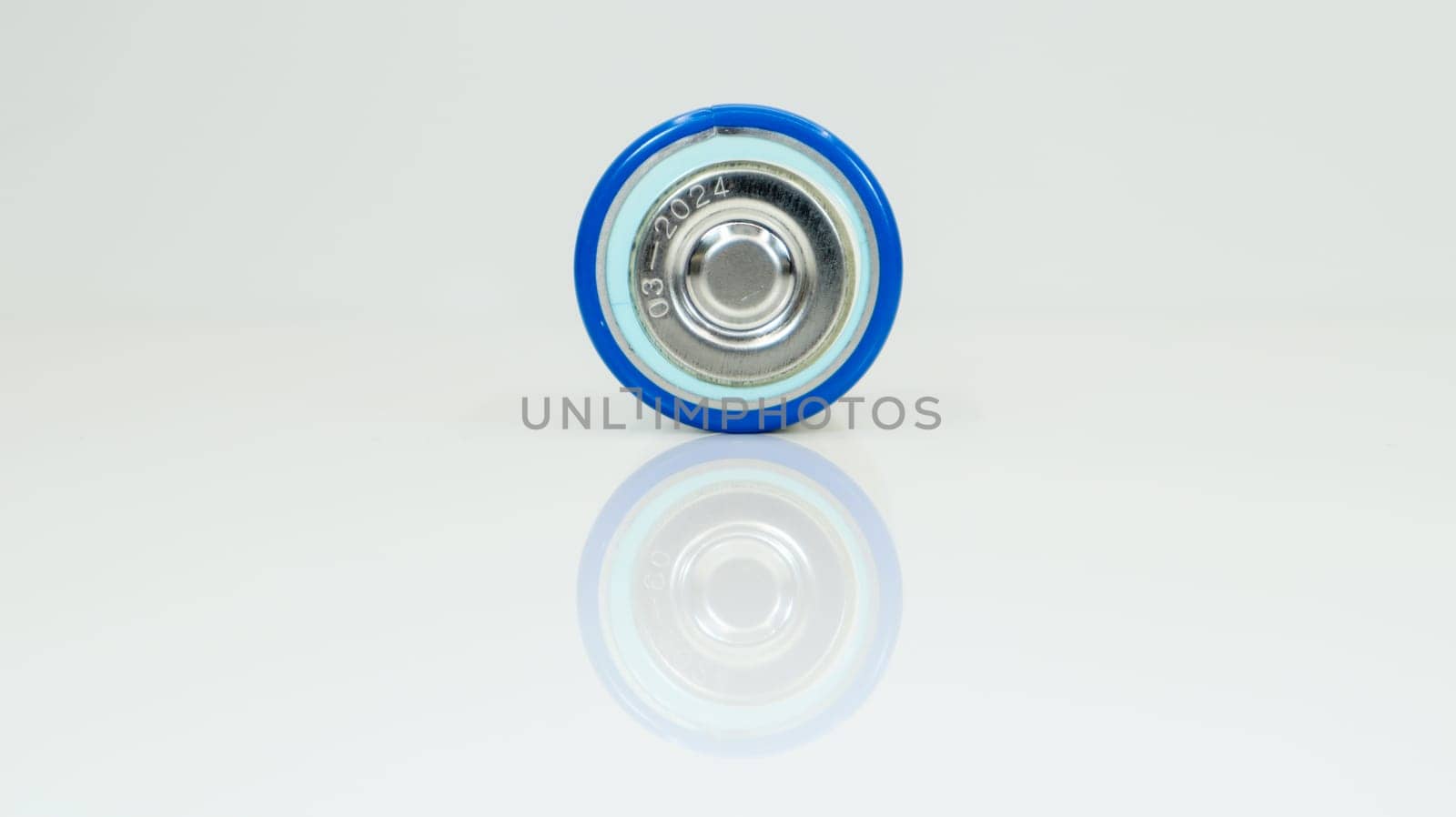 Large battery type D or C cell on white background with reflection. View of a metallic alkaline battery with copy space. Mandatory processing