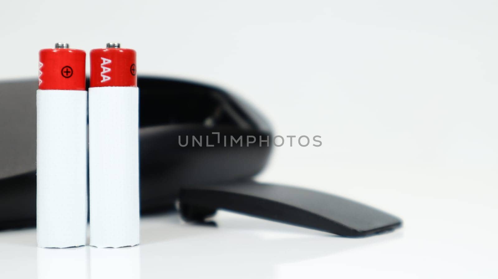 Black TV remote control with AAA alkaline batteries on a white background. Battery replacement, spare parts. Close up of an empty battery compartment of the remote control