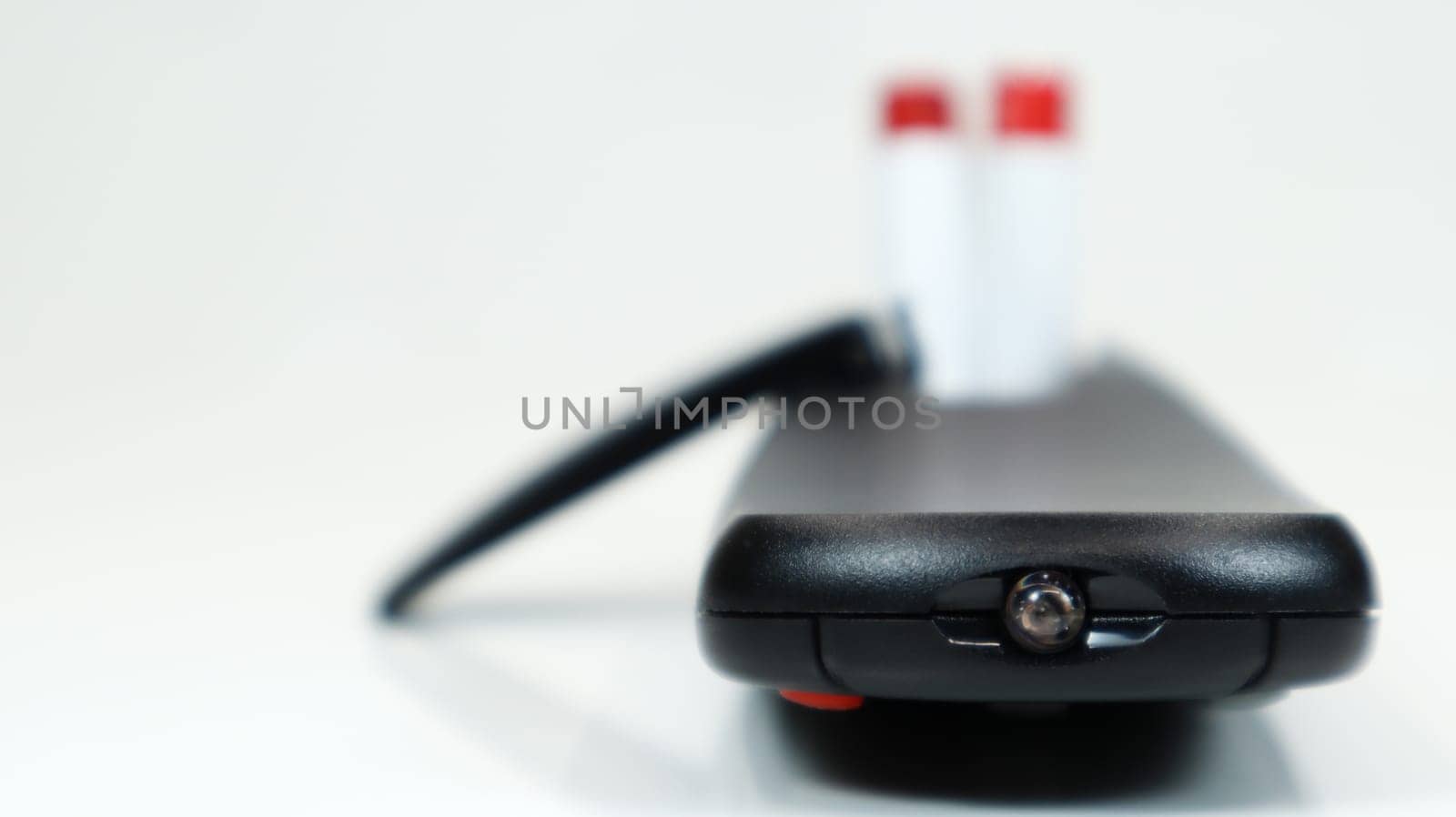 Black TV remote control with AAA alkaline batteries on a white background. Battery replacement, spare parts. Close up of the battery compartment of the remote control