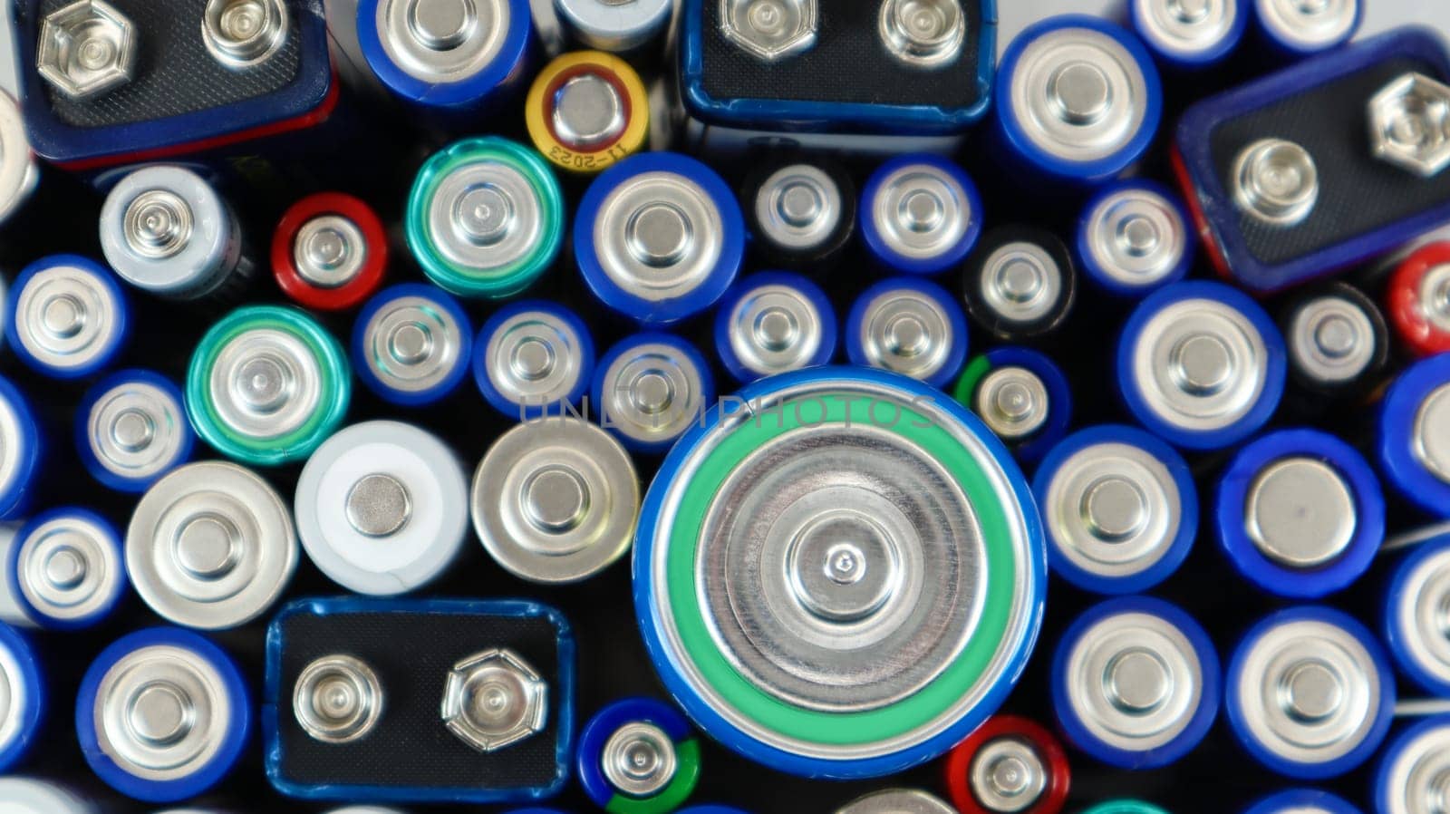 Lots of used household alkaline batteries type AA, AAA, PP3, D, C, collected for recycling. Recycling and ecology problems. Top view of a background of used batteries of different types and sizes