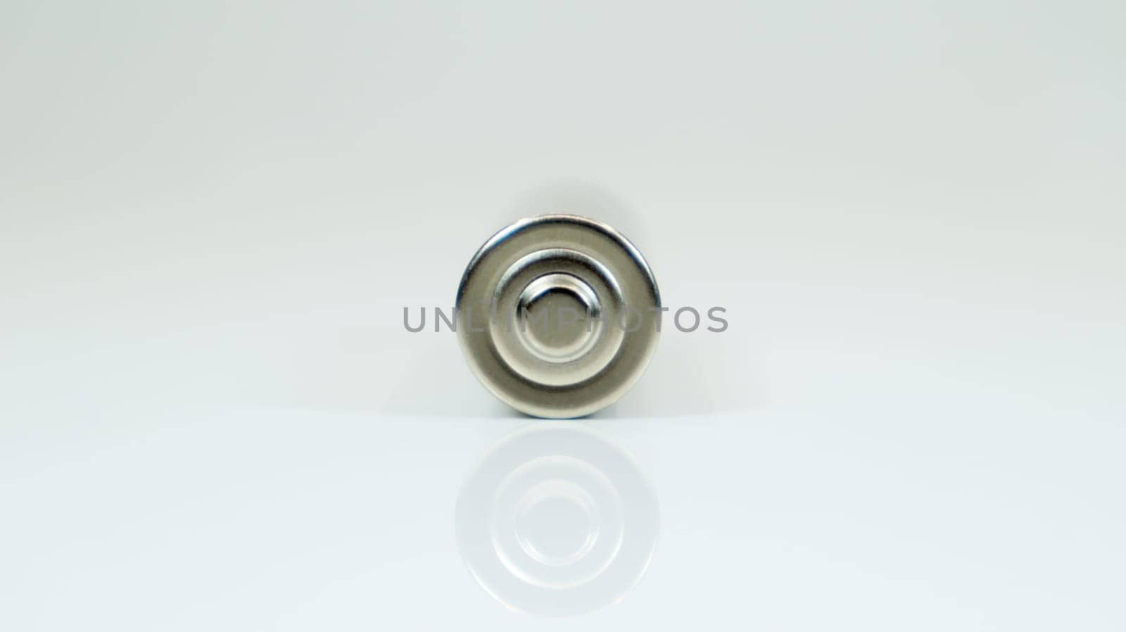 AA alkaline rechargeable battery on white glossy background with reflection. Close one empty battery with copy space