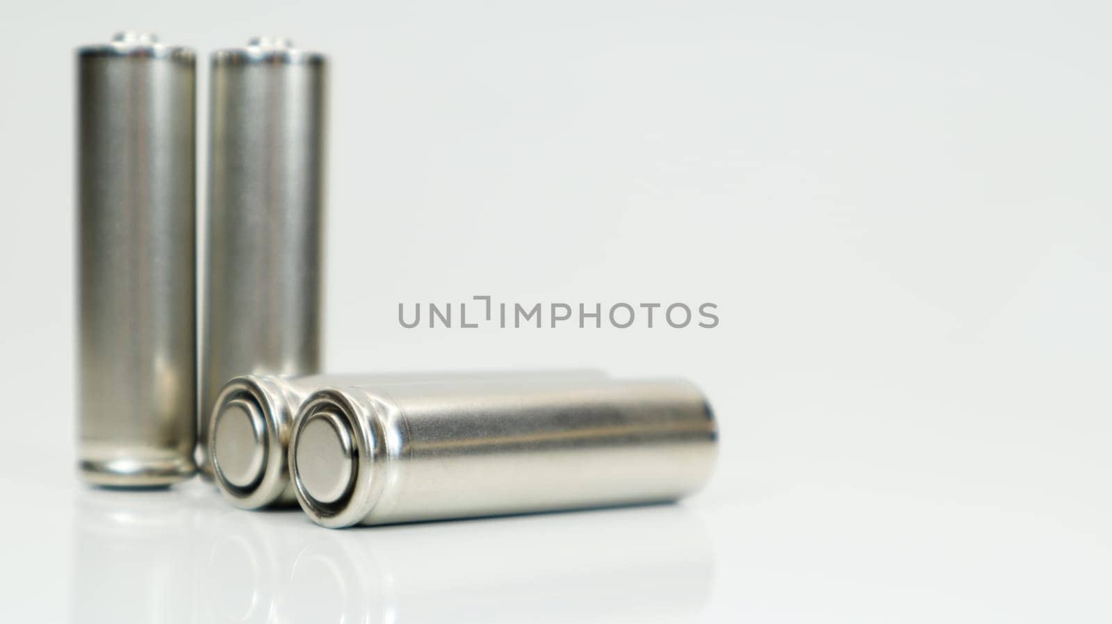 AA alkaline rechargeable batteries on white glossy background with reflection. Close up four empty batteries with copy space