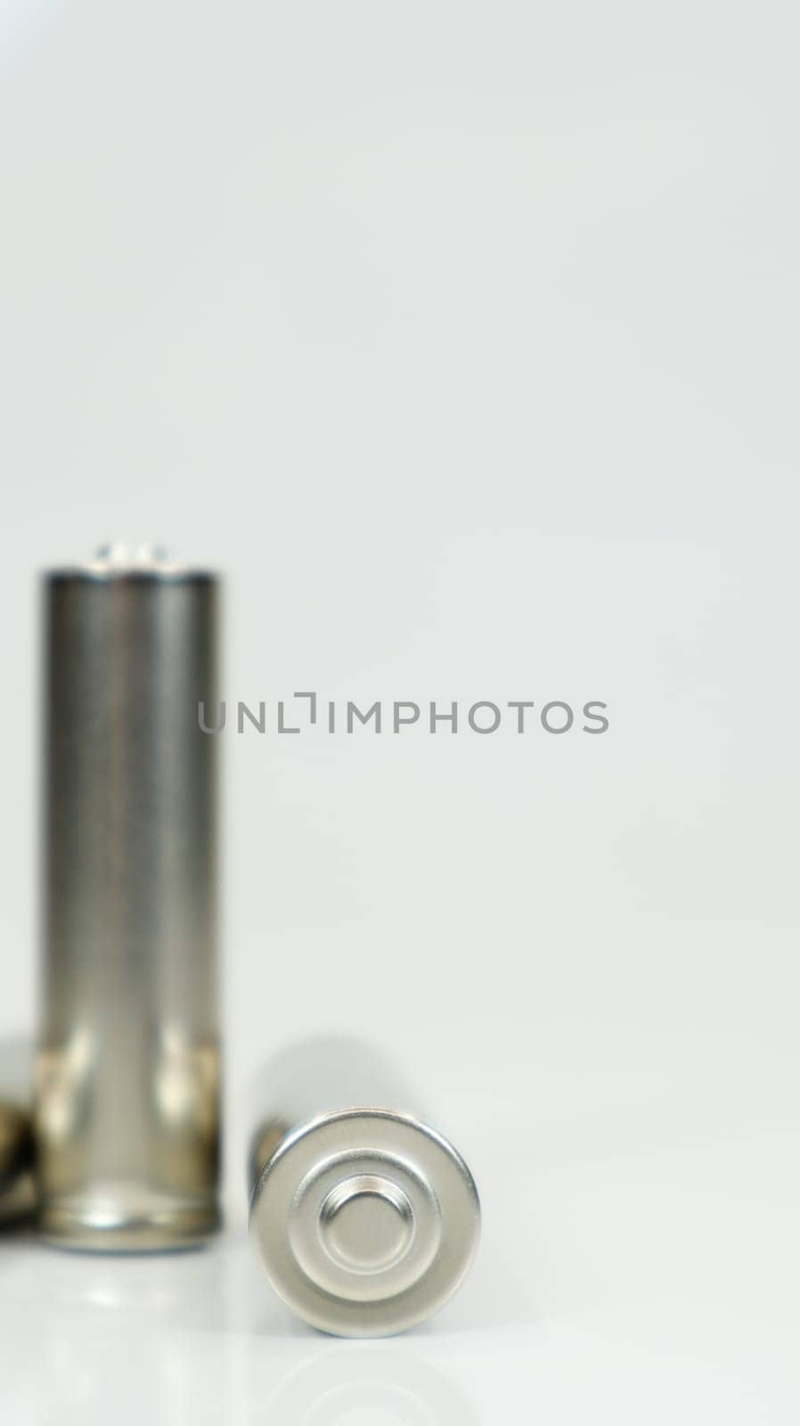 AA alkaline rechargeable batteries on white glossy background with reflection. Close up two empty batteries with copy space. Vertical photography