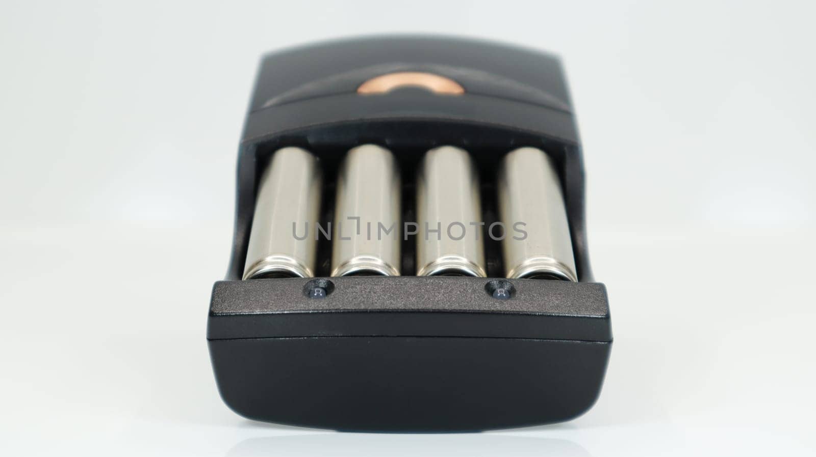 Rechargeable alkaline batteries in a battery charger on a white background. AA fast charger in black. The battery is charging