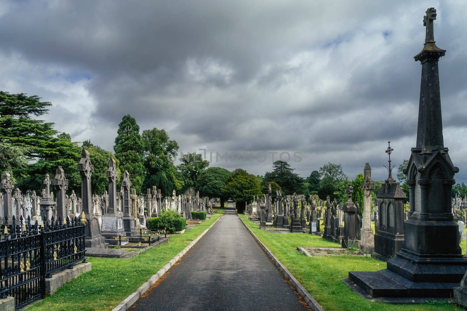 Dublin, Ireland, August 2019 Alley leading through Glasnevin Cemetery between graves with Celtic crosses and sculptures