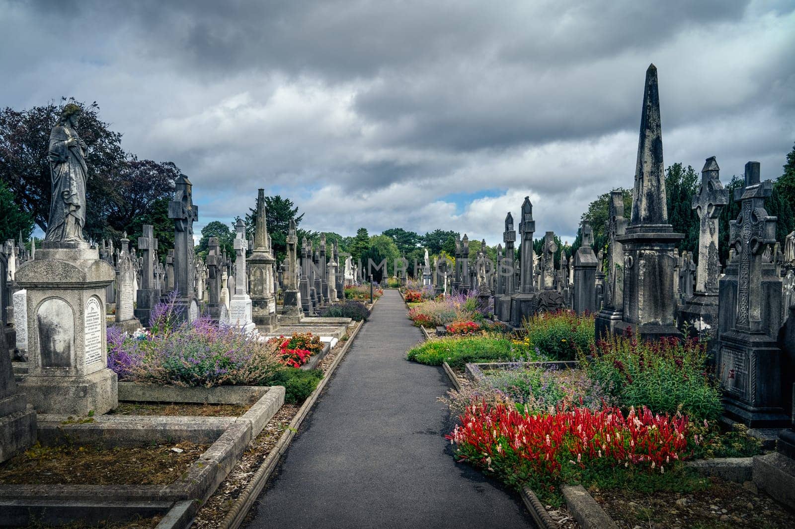 Dublin, Ireland, August 2019 Ancient graves with Celtic crosses and sculptures in Glasnevin Cemetery with dramatic storm sky in background