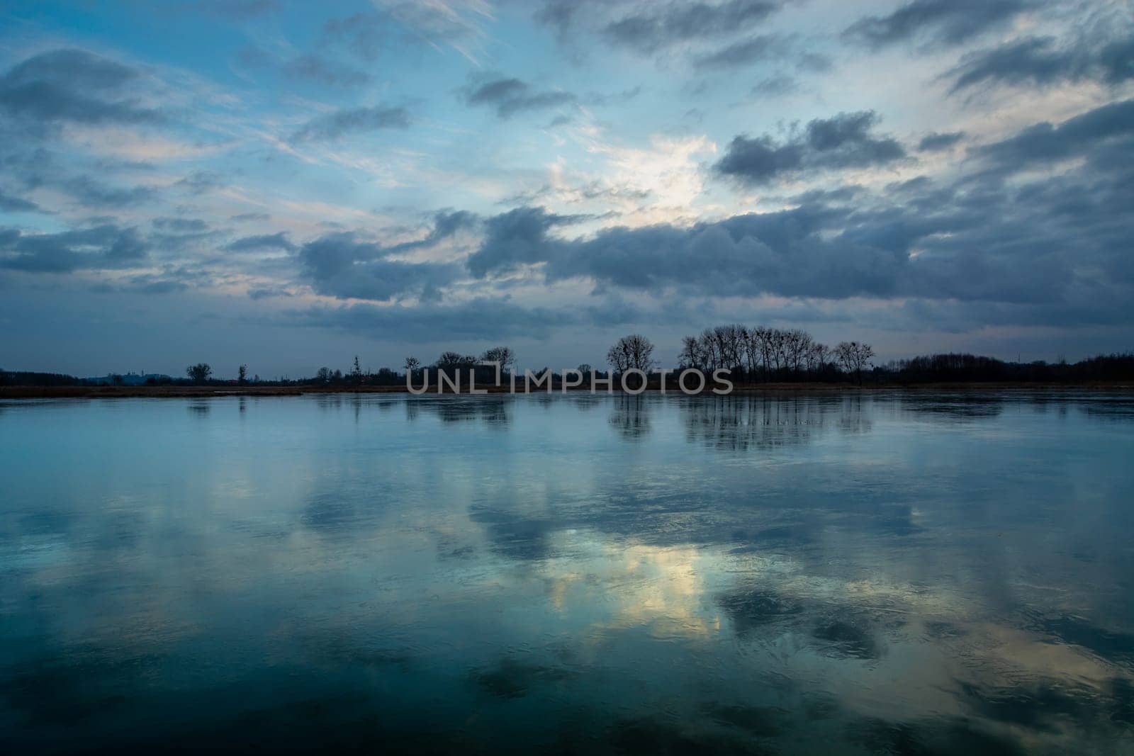 Reflection of evening clouds in a frozen lake, Stankow, Poland