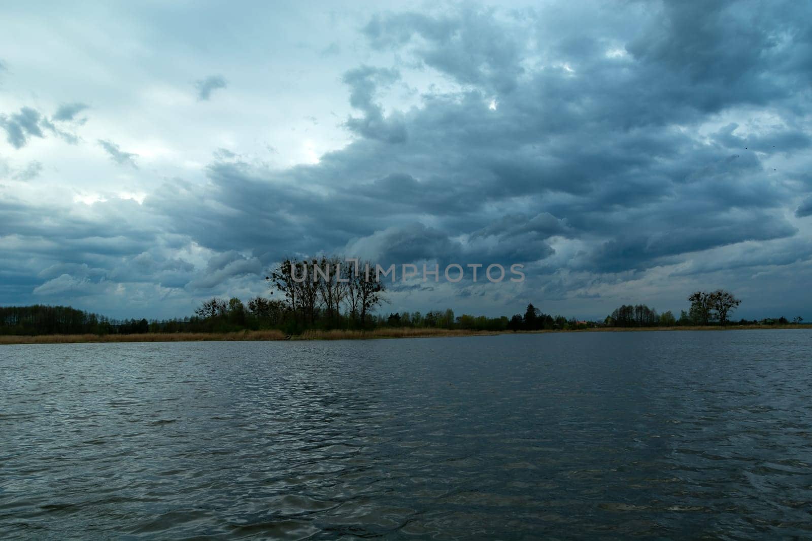 Restless evening clouds over a calm lake, spring view in Stankow, Poland