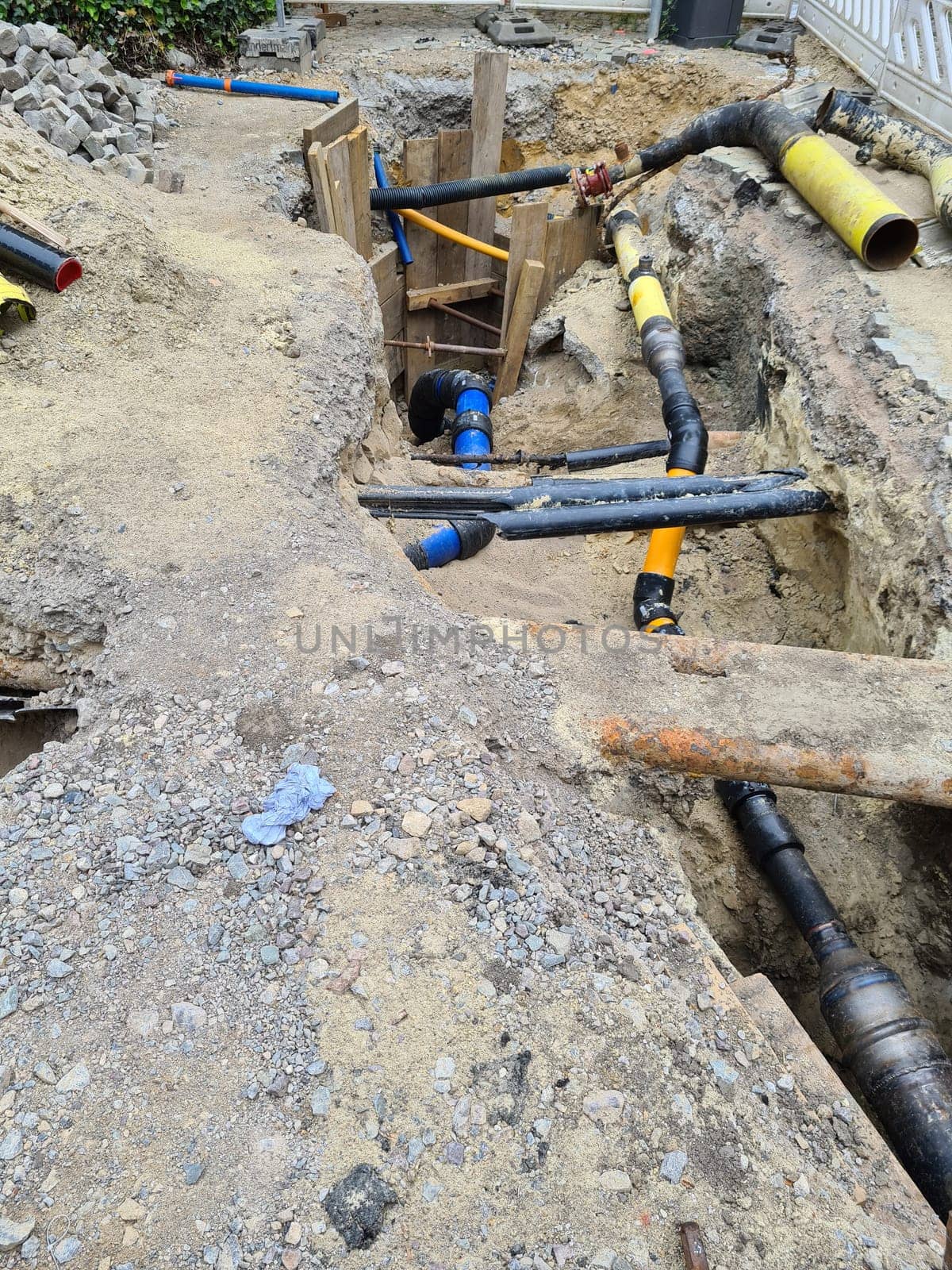 Work on the installation of engineering and heating systems. Two plastic pipes one yellow for gas pipe and one black for power lines. They are in a sand ditch.