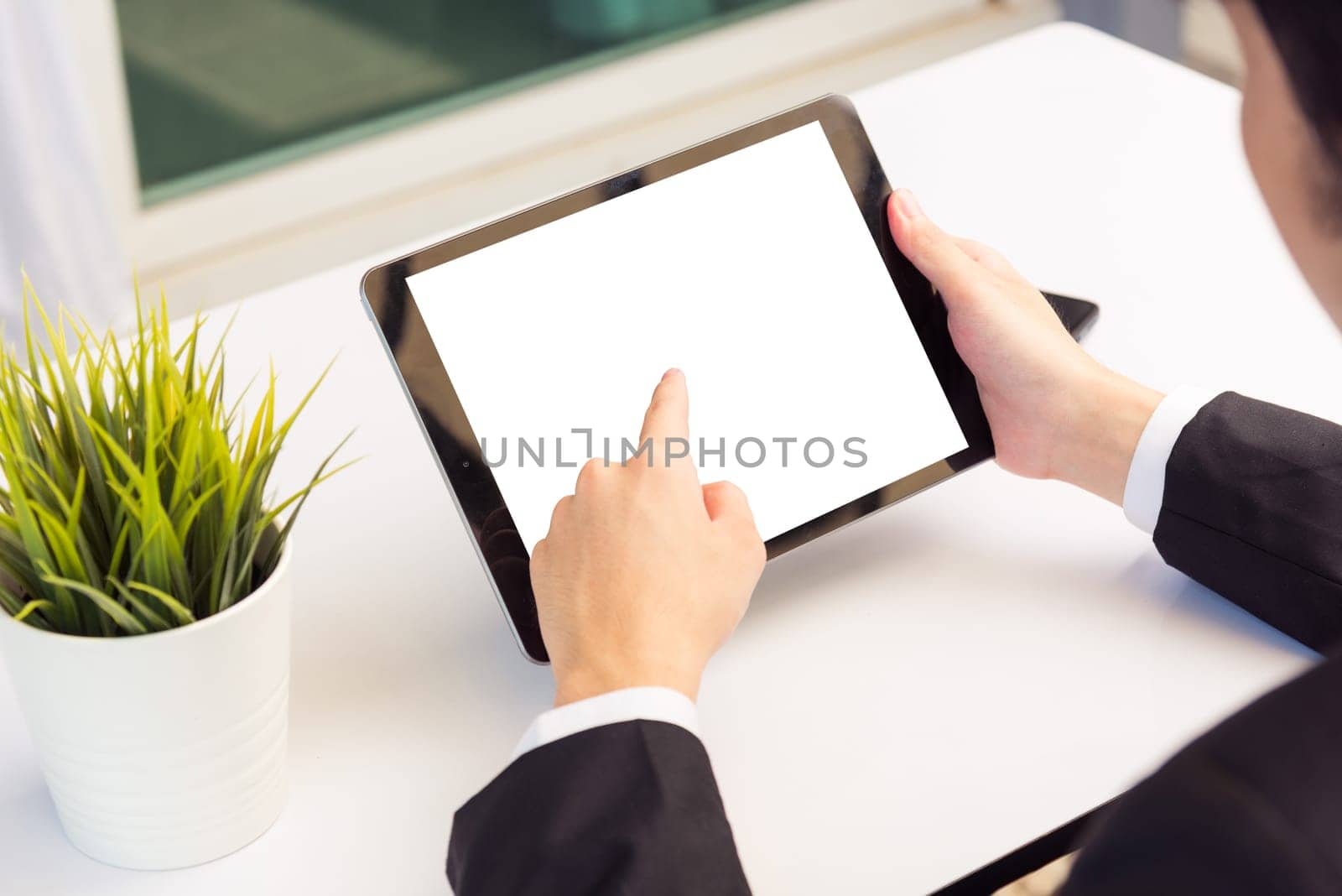 Work from home, Back view of Asian young businessman smile wearing suit video conference call or facetime by smart digital tablet computer he use finger touch on blank screen of tablet on desk