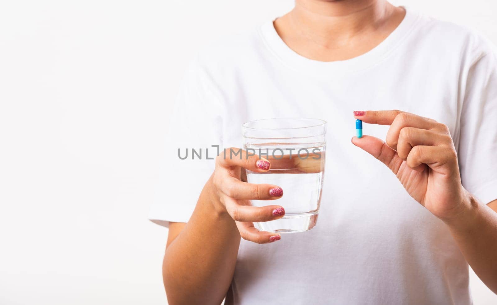 Closeup young Asian woman hold pill drugs in hand ready take medicines with a glass of water, studio shot isolated on white background, Healthcare and medical pharmacy concept