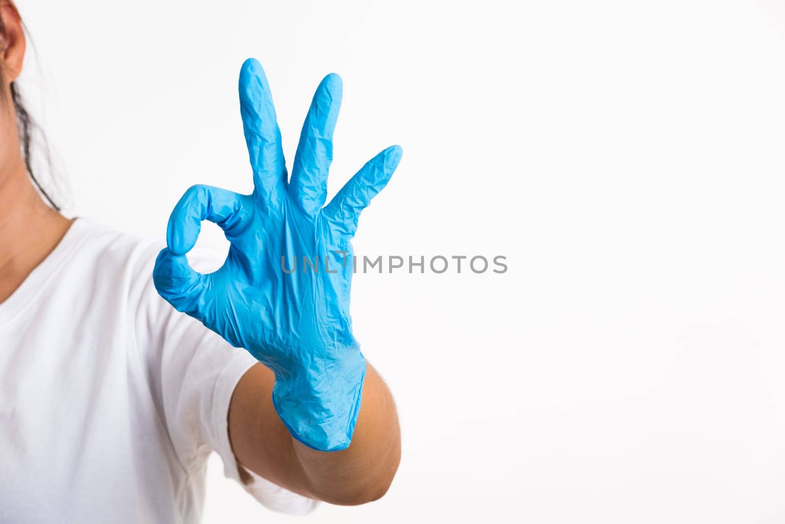 Woman wearing and putting hand to blue rubber latex glove for doctor with OK sign gesturing, studio shot isolated on white background, Hospital medical safety concept