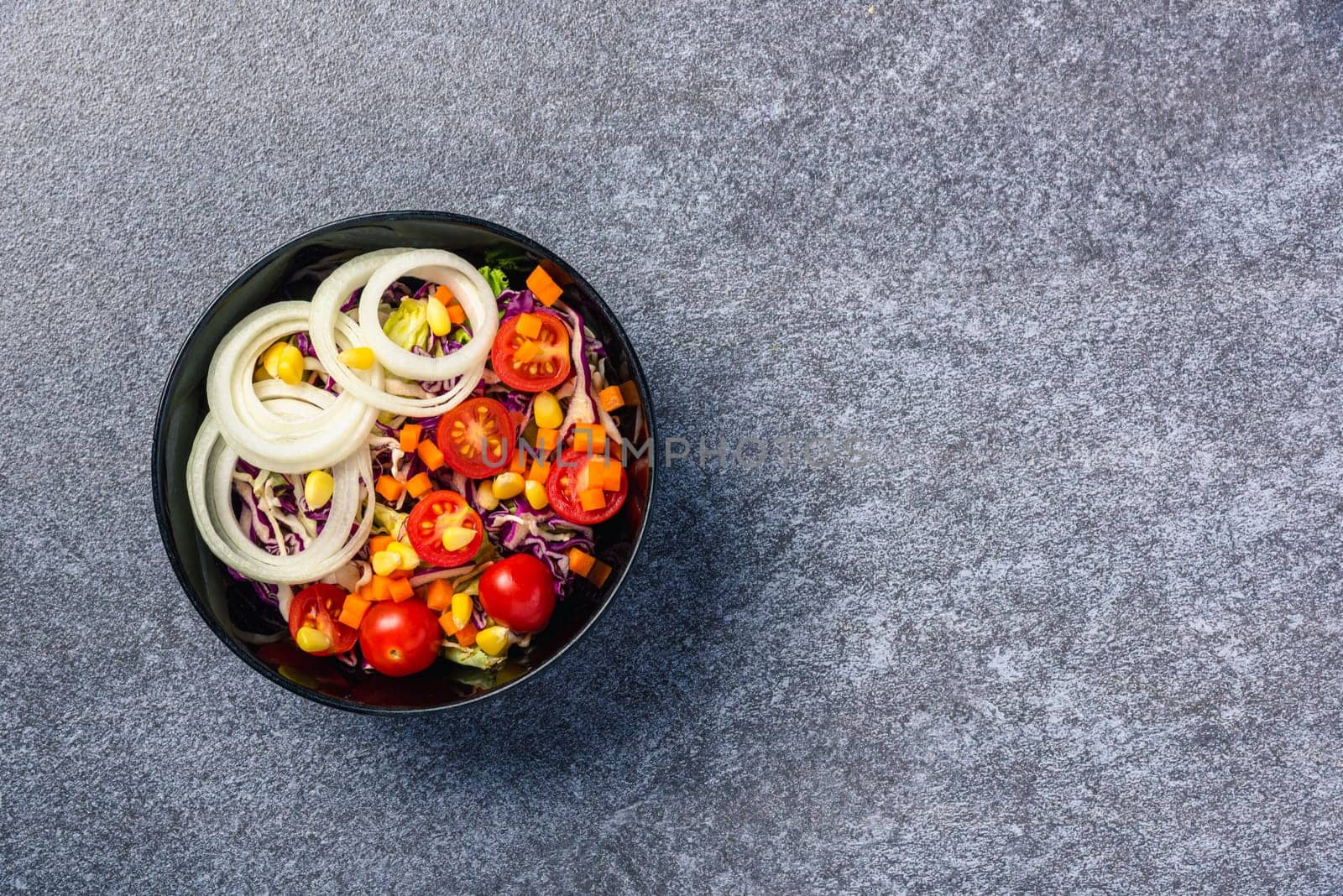 Top view of the healthy colorful salad bowl with tomatoes fresh mixed leaves vegetable in a dish on cement stone table background, Health salad snack diet food weight loss concept