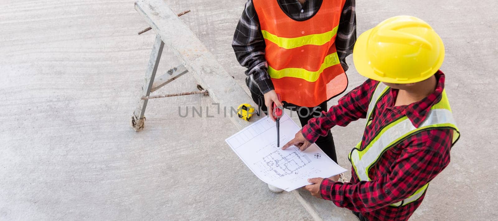 Architect and client discussing help create plan with blueprint of the building at construction site floor. Asian engineer foreman worker man and woman meeting and planning construction work, top view