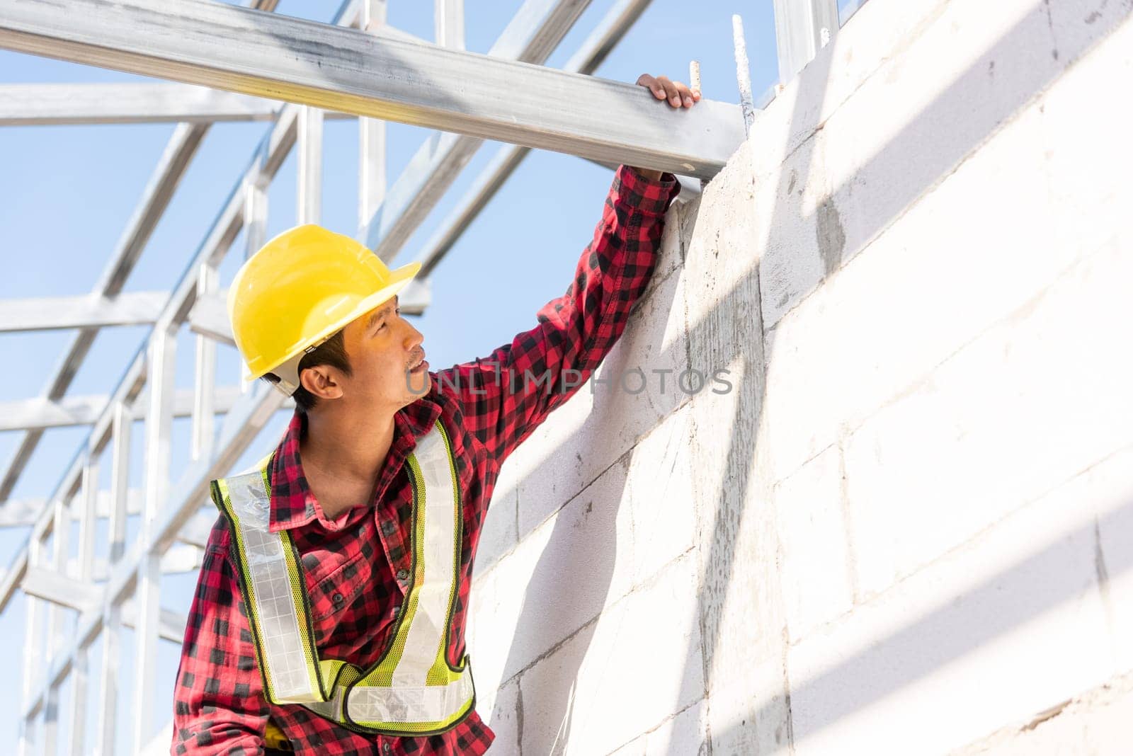 Construction worker or contractor checking house frame, worker roofer builder working on steel roof structure on building  construction site