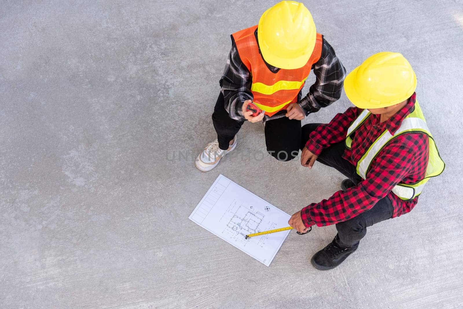 Architect and client discuss help create plan with blueprint of the building at construction site floor. Asian engineer foreman worker man and woman meeting talking on drawing paper project, top view