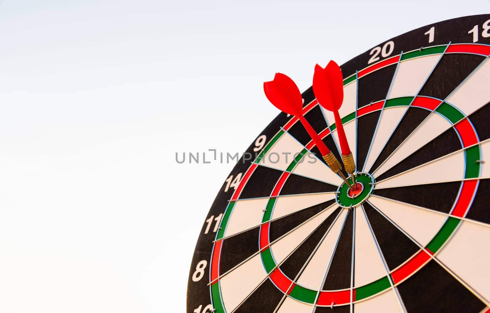 Dart arrow hitting to center on bullseye (bull's-eye) dartboard is the target of purpose challenge business at sunset, expert marketing strategy target, objective financial and goal success