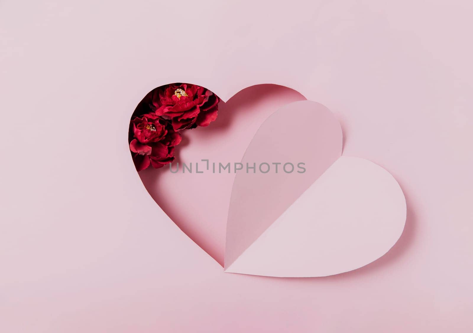 Love message, Saint Valentine Day conceptual flat lay. Top view on cut, curved paper pink heart shape on pink background. Minimal mockup for valentine card, invitation, greeting card. Red rose flower